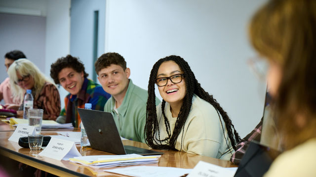 A table read featuring actors from Channel 4's series Big Boys. The actors are looking left down the table and laughing.